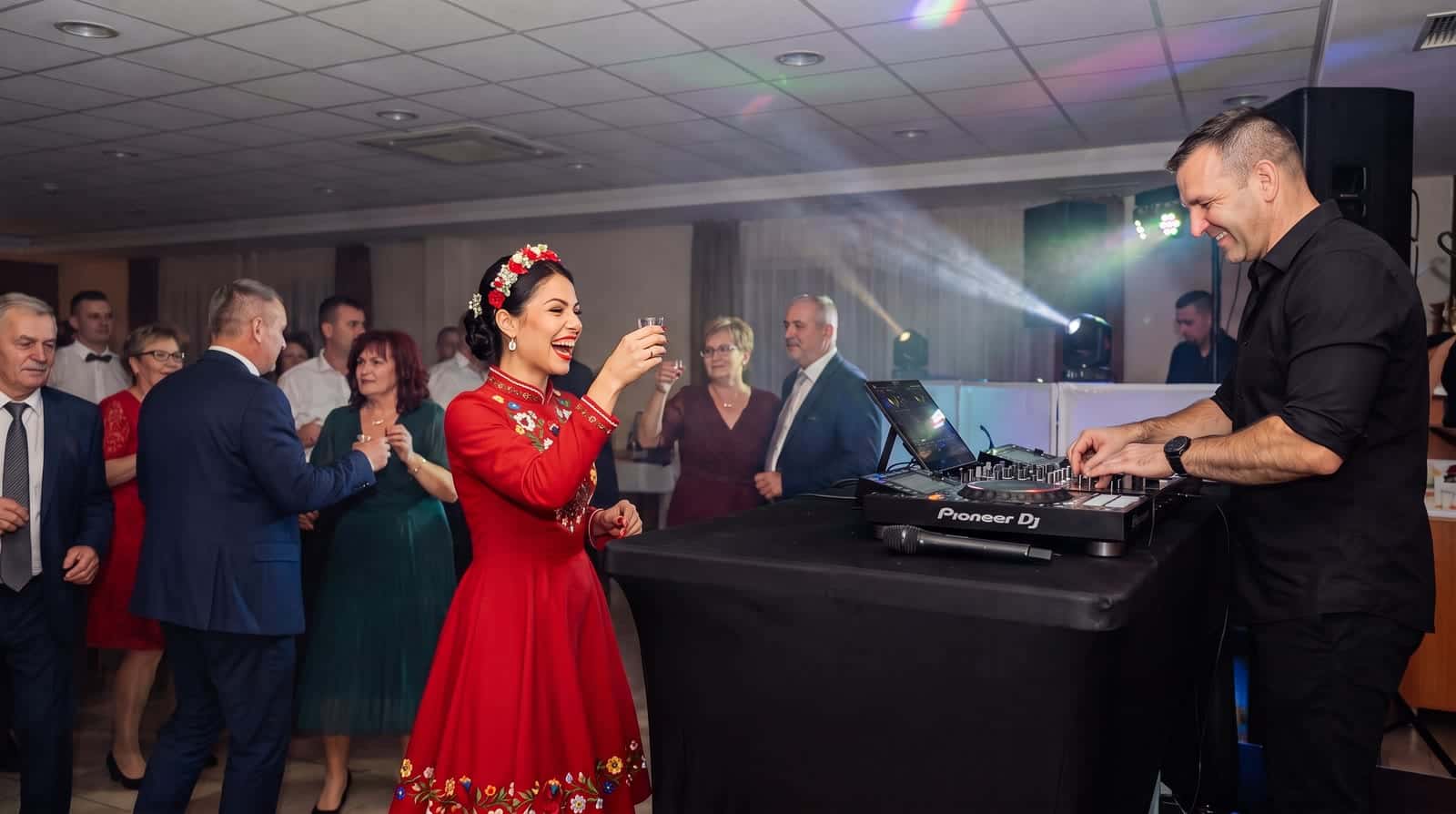 Lakodalmas zenék 2027: régi, mulatós és modern slágerek, amikre mindenki táncol 5 esküvői DJ a Pioneer pult mögött, lakodalmas zenék alatt koccint a piros ruhás menyasszony a násznéppel